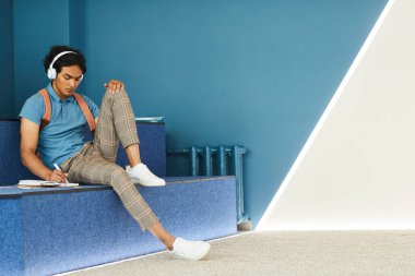 Koyu tenli öğrenci not defterine yazıyor.