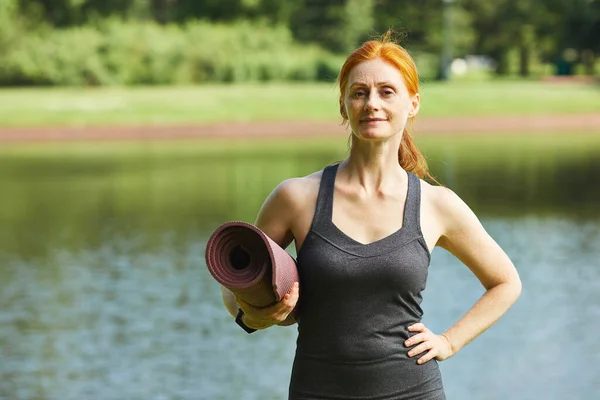 Självsäker kvinna med yogamatta — Stockfoto