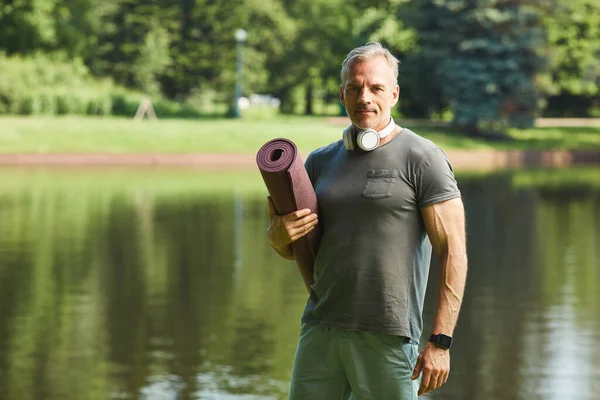 Homem muscular com tapete de exercício — Fotografia de Stock