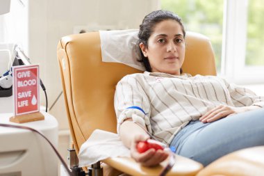 Kateterle kanepede yatan ve hastanede kan bağışı yapan kadın donörün portresi.