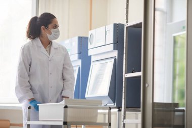 Laboratuvarda çalışan beyaz önlüklü bilim adamı tıbbi malzemeler arasında çalışıyor.