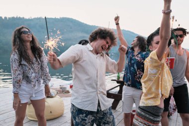 Bir grup mutlu genç havai fişek ile partide dans ediyor.