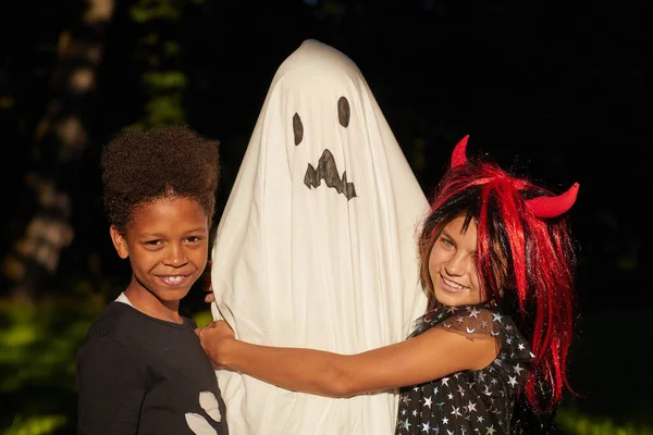 Child in ghost costume with friends — Stock Photo, Image