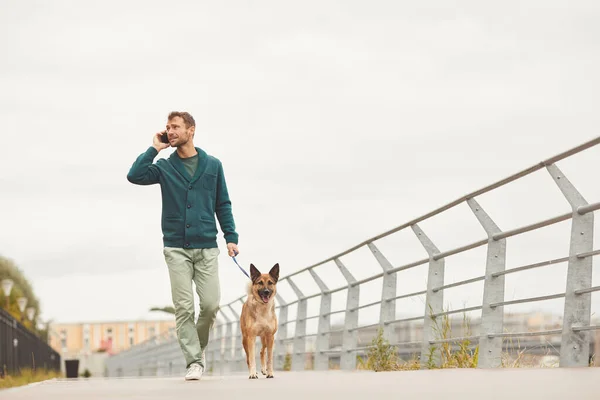 Hombre con perro paseando por la ciudad — Foto de Stock