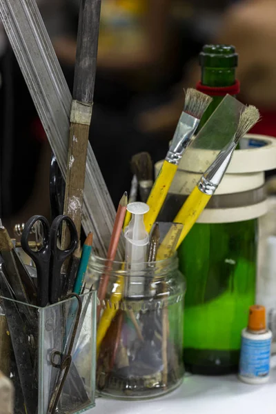 Bir sanatçı atölyesi atölyesinde cam bir kavanoz içinde diğer sanatsal araçlar arasında boya fırçaları yakın natürmort