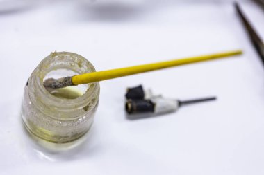 Bir sanatçı atölye küçük bir cam tutkal kavanoz içinde dinlenen sarı boya fırçası yakın