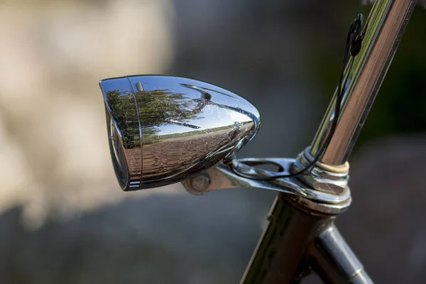 Vintage bicycle head lamp with reflection of steering wheel and out of focus blurry background