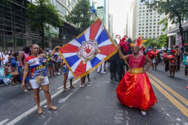 Rio de Janeiro, Brezilya - Mart 3, 2014: Rio de Janeiro şehir merkezinde bir karnaval blok partide şenlikli kostümleri samba okul bayrağı taşıyan insanlar