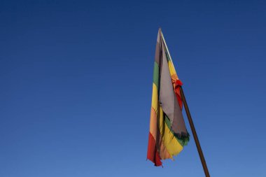 Yıpranmış ve yıpranmış baş aşağı gökkuşağı renkli Lgbt bayrağı bir bayrak direği üzerinde gevşek asılı açık mavi gökyüzüne karşı güçlü bir tezat