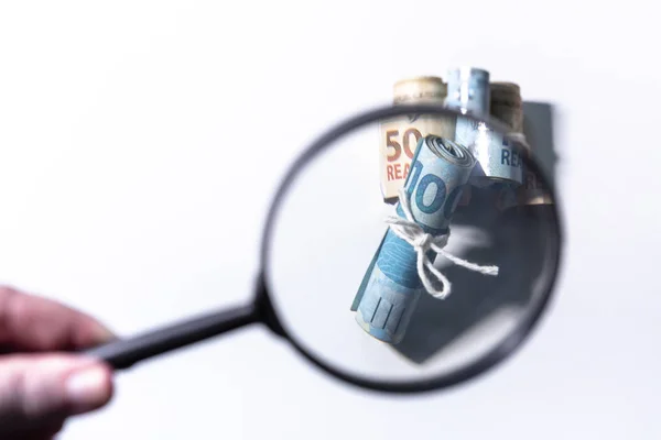 Odak dışında büyüteç banknot ruloları ayrı ayrı odak bir dize ile güvenli bakarak. Temiz stüdyo beyaz bir arka plan karşı büyütme aracı ile para vurdu.