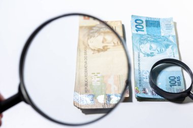 Büyük büyüteç farklı bir yığının üstüne daha küçük bir büyüteç ile banknot yığınının görüntü artırılması. Temiz stüdyo beyaz bir arka plan karşı büyütme aracı ile para vurdu.