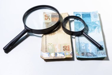 50 ve 100 Reais banknotüstüne büyük ve küçük büyüteç. Temiz stüdyo beyaz bir arka plan karşı büyütme aracı ile para vurdu. 