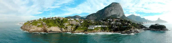 Panoramic overview of the coastline and beach of Joatinga in Rio de Janeiro with its beautiful picturesque natural richness and far in the background the well known landmark peaks of the city