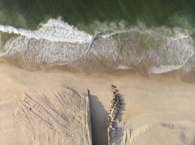 Kısmen inşa edilmiş ve kısmen yerleştirilmiş kayaların şehir gölüne giden bir kanal contrived ağız ile bozulmamış bir Leblon sahilde gelen dalgalar.