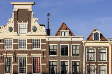 Gün batımında güneşli bir günde mavi gökyüzüne karşı Hollanda'da kanal evlerin tipik klasik Hollanda cepheleri