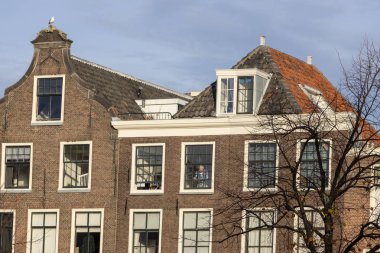 Leiden, Hollanda - 14 Kasım 2018: Hollanda'da güneşli bir günde mavi gökyüzüne karşı kanal evlerinin tipik klasik Hollanda cepheleri