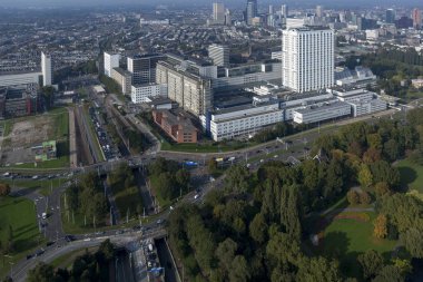 Rotterdam, Hollanda - 26 Eylül 2017: Ön planda trafik kavşağı bulunan bir şehir parkının ağaç tepelerinden yükselen Erasmus akademik hastanesinin yüksek katlı binası