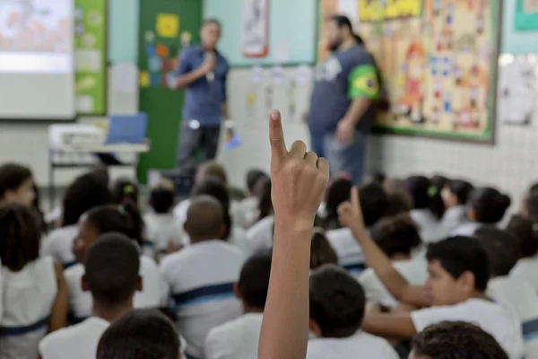 Rio de Janeiro, Brezilya-2 Temmuz 2015: bir erkek kol ile Brezilyalı sınıf ön planda bir soru sormak için bir parmak sesi gösteren ve onun eşleri ve öğretmenler arka planda bulanık