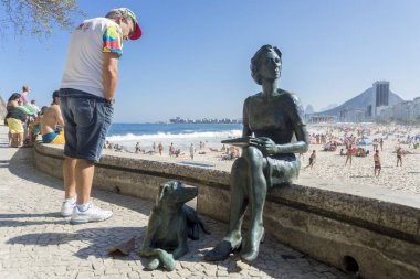 Rio de Janeiro, Brezilya-14 Ağustos 2016: Boulevard, bir köpek ile bir kadın, ön planda Clarice Lispector bir heykelin yanında metin okuma turist ile Copacabana plaj mahallesinde