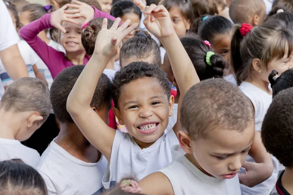 Rio de Janeiro, Brezilya-2 Temmuz 2015: genç Brezilyalı öğrenci onun sınıf arkadaşları arasında kamera gülümseyen mutluluk havası kollarını sallayarak
