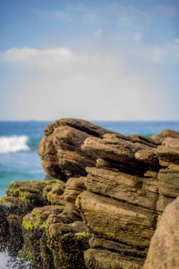 Kıyı üzerinde kayalar ve odak dalgalar dışında gelen deniz manzarası