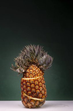 Eğer koyu yeşil bir arka plan karşı beyaz bir yüzey üzerinde sarı hamuru ve olağanüstü üst görebilirsiniz sarı çizgiler ile dik ayakta dilimlenmiş ananas
