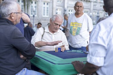 Rio de Janeiro, Brezilya - 28 Temmuz 2017: Yaşlılar yerel bir parkta toplanarak taş masalarda kart oyunları oynuyorlar. Yaşlı erkekler emeklilik zevk için bir meydanda sosyal toplama.