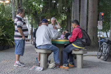 Rio de Janeiro, Brezilya - 28 Temmuz 2017: Yaşlılar yerel bir parkta toplanarak taş masalarda kart oyunları oynuyorlar. Yaşlı erkekler emeklilik zevk için bir meydanda sosyal toplama.