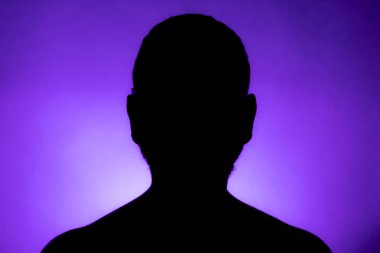 Büstü hemen arkasında bir spot ışığı ve parlak alan ile mor bir arka plan karşı bir erkek kişinin temiz tanımlanmış ön siluet. Stüdyo iyi tanımlanmış açık renk arka plan ile çekim.