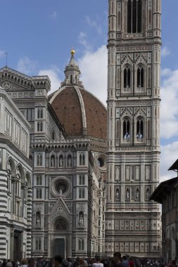 Turistlerle dolup taşan bulutlu ve kareli mavi gökyüzüne karşı Floransa'nın kubbesi ile kule ve ortaçağ katedralinin mimarisi