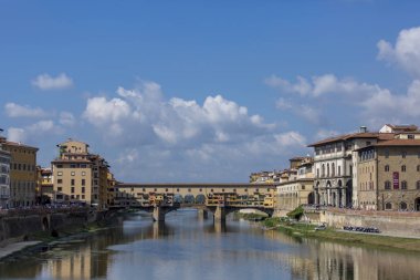 Orta Çağ Vecchio köprüsü ve Floransa'nın rönesans mimarisi, Arno Nehri'nden mavi bir gökyüzüve bulutlara karşı görüldü
