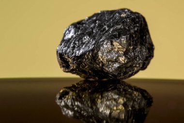 Turuncu bir arka plan aleyhine parlayan altın özelliklere sahip ağır mineral kaya küçük bir parça