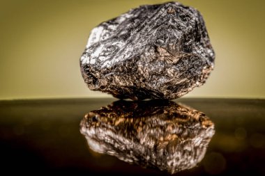 Koyu bir dış ve altın özellikleri ile ağır mineral kaya küçük bir parça turuncu bir arka plan karşı parlayan
