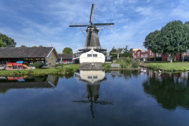 Utrecht bir mahallede Woodworking yel değirmeni, Hollanda, mavi gökyüzü ile parlak güneşli bir günde önünde kanal içinde su aynalı.