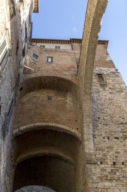 Açık mavi gökyüzüne karşı aşağıdan görülen tuğla yay ile Siena İtalyan kentinde Ortaçağ mimarisi