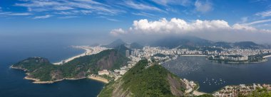 Rio de Janeiro'nun hava şehir manzarası panoraması, sağda copacabana ile şehrin üzerinde oluşan bulutlar ve sağda botafogo mahallesi ile oluşan mavi gökyüzüne karşı doğal manzara