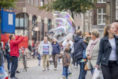 Groningen, Hollanda - 1 Ekim 2016: Piyasadaki insanların eğlencesine dev sabun kabarcıkları yapan ve özellikle Groningen Cumartesi pazarındaçocukların dikkatini çeken adam