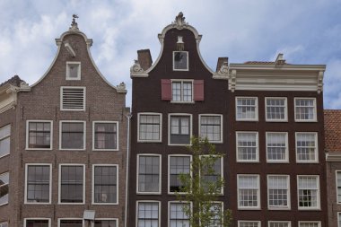 Amsterdam'da tipik kanal evlerinin cepheleri, otantik tarihi mimarisi ve özel atmosferi ve güzelliği için turistler arasında popüler