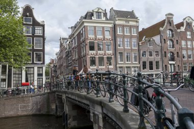 Bulutlu bir günde bisikletve tipik kanal evleri ile Amsterdam kanal köprüsü