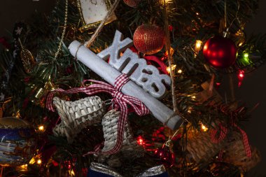 Sıcak renklerde çan ve diğer dekorasyon ile ortasında Xmas olarak hecelenen kelime Noel ile Atmosferik Noel ağacı dekorasyon