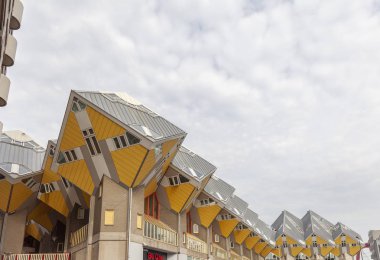 Rotterdam, Hollanda - 28 Ağustos 2019: Rotterdam'da bulutlu bir gökyüzüne karşı ünlü eğimli küp evlerin bir sıra ile sokak görünümü
