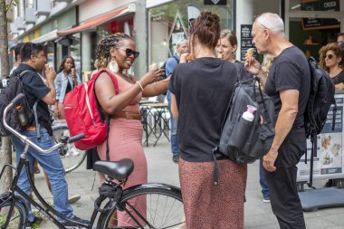 Rotterdam, Hollanda - 28 Ağustos 2019: Çeşitli milletlerden bir grup insan Rotterdam sokaklarında bir dondurma dükkanının önünde dondurma yiyor ve sohbet ediyorlar.