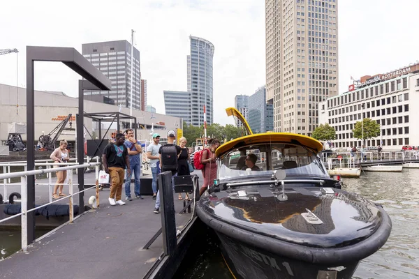 Rotterdam, Hollanda - 28 Ağustos 2019: Rotterdam şehir merkezindeki liman bölgesinde bulunan su taksisi, insanların arka planda yüksek binalara binmelerine izin verdi.