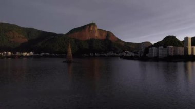 Aerial movement forward over the Rio de Janeiro city lake with the floating Christmas tree of 2018 in the middle with in the background the Corcovado mountain with the Christ statue on top at sunrise