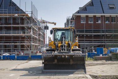 Amsterdam, The Netherlands - August 31, 2019: Modern sustainable housing in the port area of Houthaven neighbourhood with construction tools in the foreground and homes in scaffolding in the back