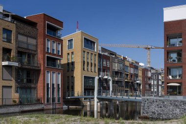 Amsterdam, Hollanda - 31 Ağustos 2019: Yeni inşa edilen Houthaven Mahallesi 'nde baba ve oğluyla birlikte ön planda köprüden geçen bisikletli modern mimari