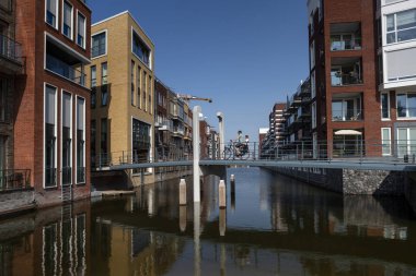 Amsterdam, Hollanda - 31 Ağustos 2019: Yeni inşa edilen Houthaven Mahallesi 'nde baba ve oğluyla birlikte ön planda köprüden geçen bisikletli modern mimari
