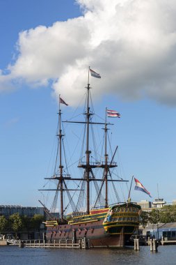 Amsterdam, Hollanda - 1 Eylül 2019: Amsterdam 'daki açık hava deniz müzesinin yanındaki tarihi yelkenli gemi bulutlu mavi bir gökyüzüne karşı
