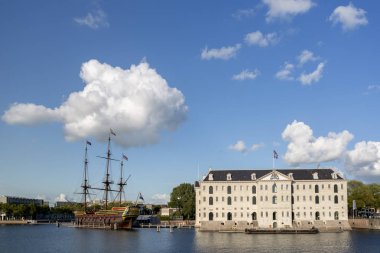 Amsterdam, Hollanda - 1 Eylül 2019: Amsterdam 'da açık hava deniz müzesi yanında tarihi bir yelkenli gemisiyle bulutlu mavi bir gökyüzüne karşı