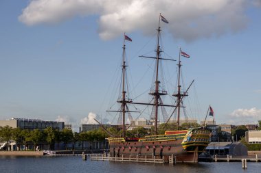 Amsterdam, Hollanda - 1 Eylül 2019: Amsterdam 'daki açık hava deniz müzesinin yanındaki tarihi yelkenli gemi bulutlu mavi bir gökyüzüne karşı